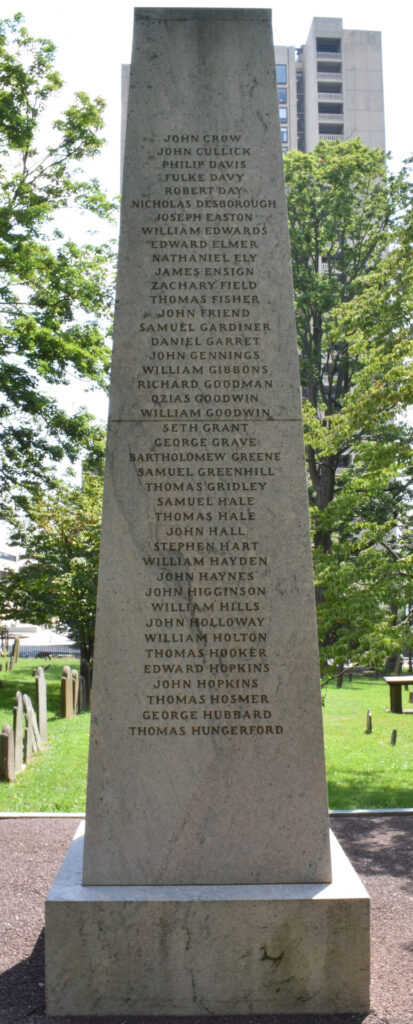 Founders Monument photo of North side. Inscription: JOHN CROW / JOHN CULLICK / PHILIP DAVIS / FULKE DAVY / ROBERT DAY / NICHOLAS DESBOROUGH / JOSEPH EASTON / WILLIAM EDWARDS / EDWARD ELMER / NATHANIEL ELY / JAMES ENSIGN / ZACHARY FIELD / THOMAS FISHER / JOHN FRIEND / SAMUEL GARDINER / DANIEL GARRET / JOHN GENNINGS / WILLIAM GIBBONS / RICHARD GOODMAN / OZIAS GOODWIN / SETH GRANT / GEORGE GRAVE / BARTHOLOMEW GREENE / SAMUEL GREENHILL / THOMAS GRIDLEY / SAMUEL HALE / THOMAS HALE / JOHN HALL / STEPHEN HART / WILLIAM HAYDEN / JOHN HIGGINSON / WILLIAM HILLS / JOHN HOLLOWAY / WILLIAM HOLTON / THOMAS HOOKER / EDWARD HOPKINS / JOHN HOPKINS / THOMAS HOSMER / GEORGE HUBBARD / THOMAS HUNGERFORD