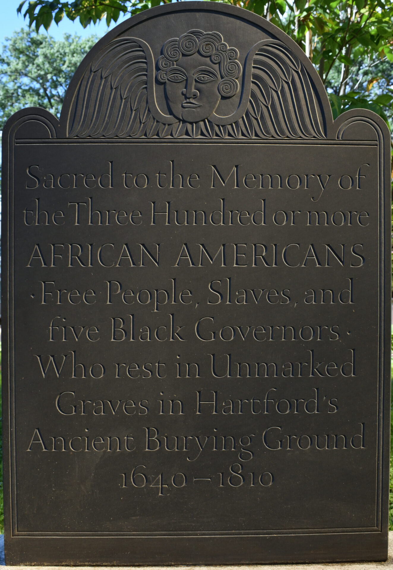 Monument at Hartford's Ancient Burying Ground with inscription that says "Sacred to the Memory of / the Three Hundred or more / AFRICAN AMERICANS / Free People, Slaves, and / five Black Governors / Who rest in Unmarked / Graves in Hartford’s / Ancient Burying Ground / 1604-1810"